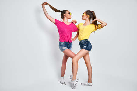 Two young beautiful smiling international hipster female in trendy summer clothes. Sexy carefree women posing on white background in studio.の写真素材
