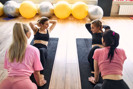 girl in the gym doing exercises for the press, teamwork