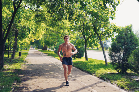 A strong attractive man running shirtless outside in the parkの写真素材