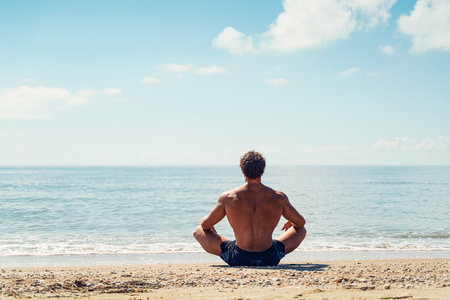 Man meditates on the sandy beach view from the backの写真素材