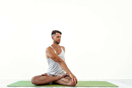 Male yoga maditates in classical pose in studio over white backgroundの写真素材