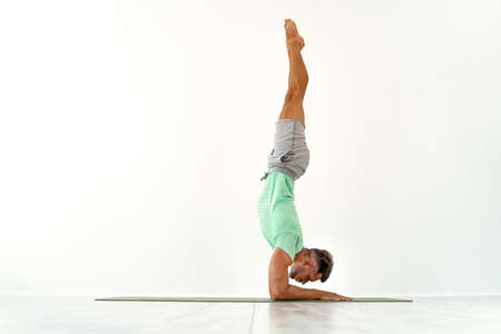 Young man acrobatics gymnastic doing a handstand studio isolated on white background, athletic...
