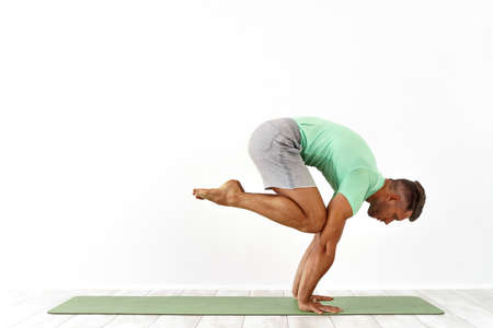 Man practicing balance yoga pose on white studio backgroundの写真素材