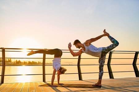 Couple doing practicing yoga together on nature outdoors . Morning exercises at the sunrise.の写真素材