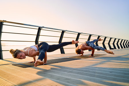 Couple doing practicing yoga together on nature outdoors . Morning exercises at the sunrise.