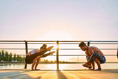 Couple doing practicing yoga together on nature outdoors . Morning exercises at the sunrise.の写真素材