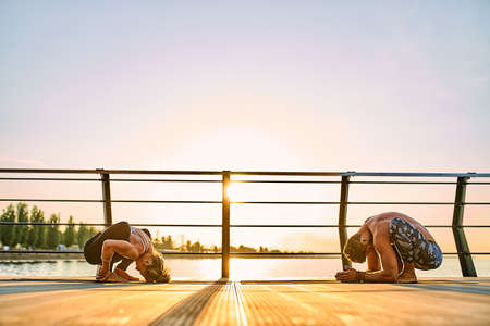 Couple doing practicing yoga together on nature outdoors . Morning exercises at the sunrise.の写真素材