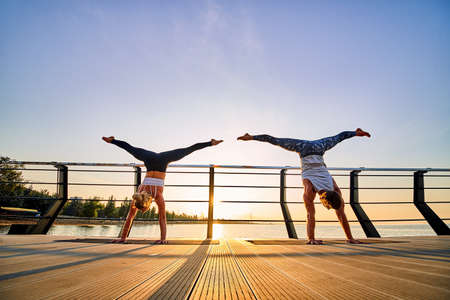 Couple doing practicing yoga together on nature outdoors . Morning exercises at the sunrise.の写真素材