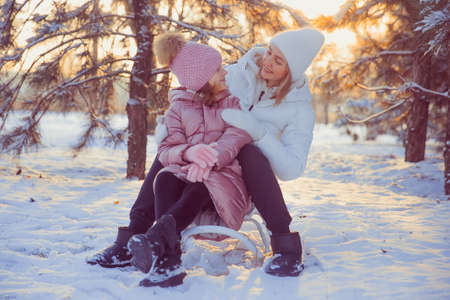 Little girl and her mother playing outdoors at sunny winter day
