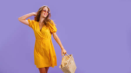 Fashionable woman in nice yellow dress and straw handbag. Fashion spring summer photo