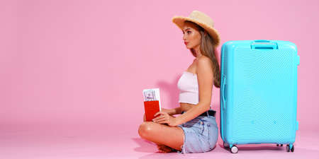 girl with a tickets and cash are going to travel. Sitting near suitcase in shorts white top and...