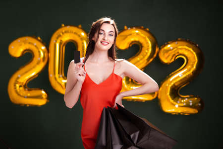 Woman with credit card and purchases. New Year shopping. Black Friday. 2022 balloons salesの写真素材
