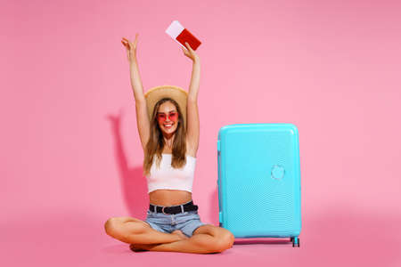 Woman tourist, traveler with passport and tickets, suitcase, white top, shorts, straw hat.の写真素材