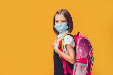 Caucasian schoolgirl in a medical mask is preparing to go to school. Virus protection for childrenの写真素材