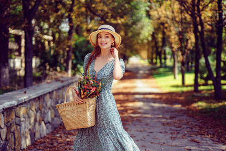 Happy smiling redhead girl in fluttering dress walks in the autumn park. Indian summer conceptの写真素材