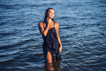 Beautiful girl in dress posing in water. tropic island girl, beautiful tan, skin care, pretty faceの写真素材