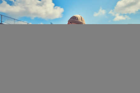 Serious student in glasses studies while sits near the university with laptop and headphonesの写真素材