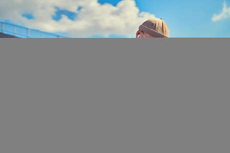 Serious student in glasses studies while sits near the university with laptop and headphonesの写真素材