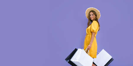 smiling woman holds packages after shopping on purple background. discounts, black Friday, sales