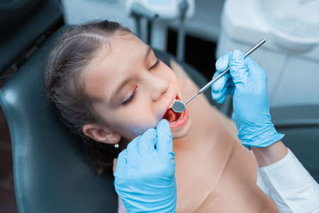 Dentist and little girl patient in the dental office. Close up of Child having teeth checking