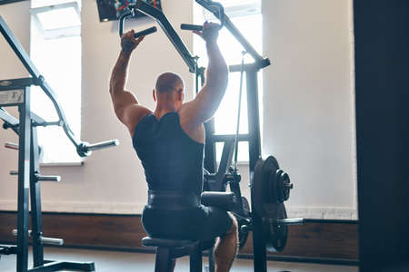 Adult bodybuilder doing heavy weight exercise for back on machine while in gym Bodybuilding conceptの写真素材