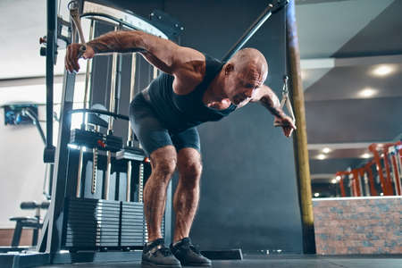 Older bodybuilder works out trains in the gym gains weight pumping up muscles. Bodybuilding conceptの写真素材