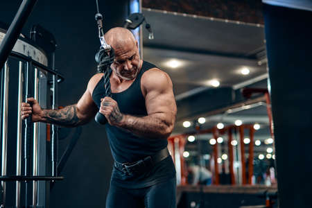 Adult athlete bodybuilder doing heavy weight exercise for triceps while in gym. Bodybuilding conceptの写真素材