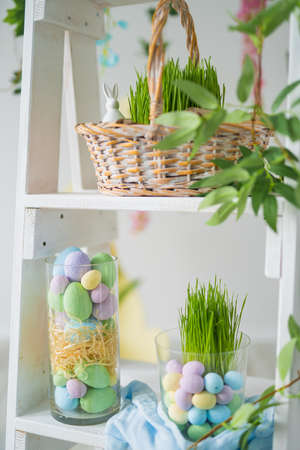 Rack with beautiful Easter decorations in room. Easter composition. Colorful dyed eggs