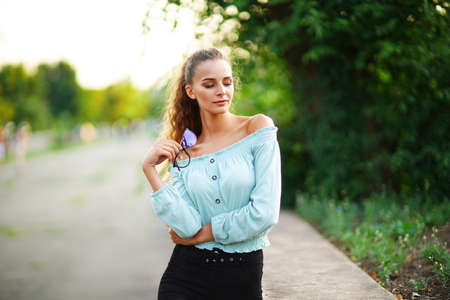 stylish beautiful young woman wears in summer bright hipster clothes while posing in the parkの写真素材