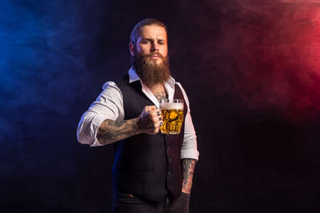Half length of hipster bearded man who holds mug of beer looking at camera over smoke backgroundの写真素材