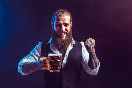 Happy bearded man holds mug of draft beer in hand while gesturing. Drinking, October fest conceptの写真素材