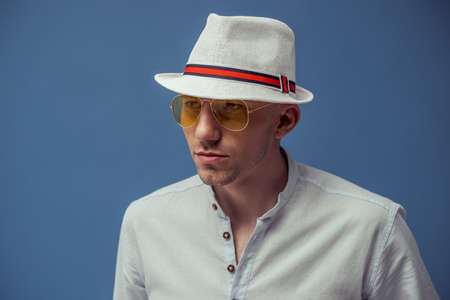 Studio portrait of young man who wears in sunglasses with elegant hat on colorful backgroundの写真素材