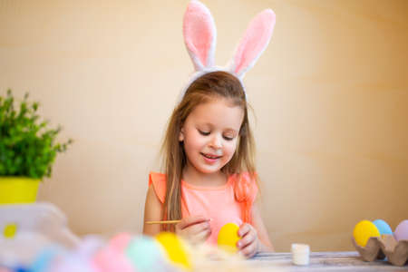 Cute child in bunnies ears prepares for Easter painted Easter eggs. Happy easter conceptの写真素材