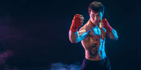 Half length of aggressive shirtless boxer who preparing for fight on dark background. Sport conceptの写真素材