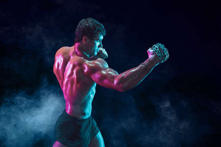 Side view of Muscular fighter who delivering hit with chain on smoke background. mixed mediaの写真素材