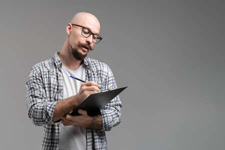 Young teacher man of university or college holds clipboard makes notes while lecturingの写真素材