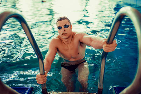 Portrait of emotional male swimmer in swimming goggles who out of the pool. Perfect bodyの写真素材