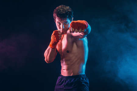 Front view of aggressive boxer who training and practicing jab on smoke background. Sport conceptの写真素材