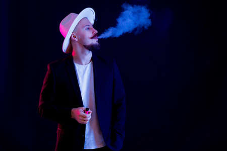 bearded man in white wide-brimmed hat vaping. concept quitting smoking submissions therapyの写真素材
