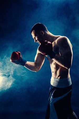 Side view of sportsman muscular boxer who fighting on black smoke background. Boxing sport conceptの写真素材