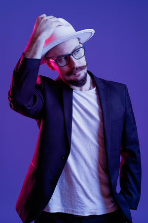 Fashionable guy. Studio shot in dark studio with neon light. Portrait of serious manの写真素材