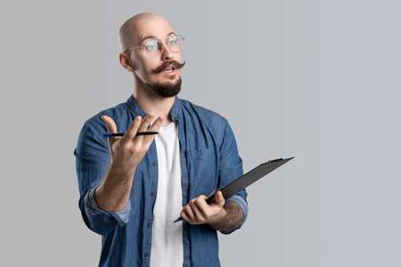 Image of handsome balded with musctache and beard man wearing casual clothes holding clipboard isolated over white background.の写真素材