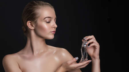 Young beautiful woman with a bottle of perfume. Model with healthy skin, close up portrait. Cosmetology, beauty and spaの写真素材