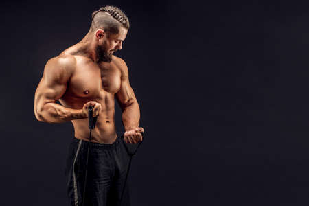 Muscular guy stretching rubber resistance bands in dark backgroundの写真素材