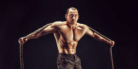 One handsome sexual strong young man, muscular body holding rope with hands hanging on neck and...