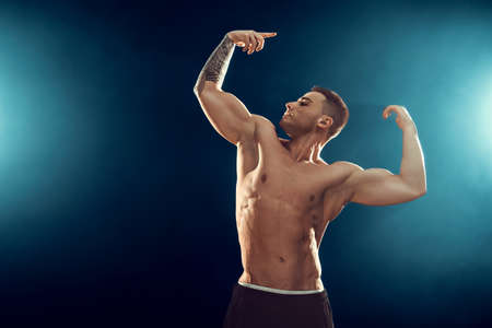 Power, strength, excellent body, bodybuilding, sports concept. Young handsome muscular fit man demonstrating perfect bodyの写真素材