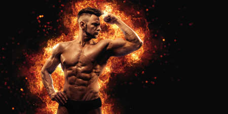 Brutal strong athletic Bodybuilder posing. Fire and spark explosion in the background.の写真素材