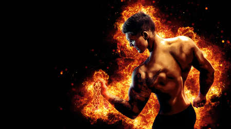 Body builder with fit torso belly chest and arms biceps triceps muscles holding chain while posing over the black background with fire. Bodybuilding conceptの写真素材