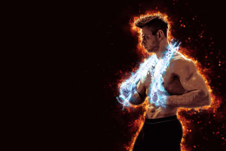 Muscular man with naked torso holding electric energy chain. Isolated on dark background with fireの写真素材