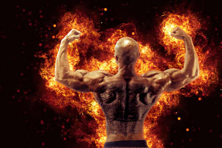 Brutal strong athletic Bodybuilder posing. Fire and spark explosion in the background.の写真素材